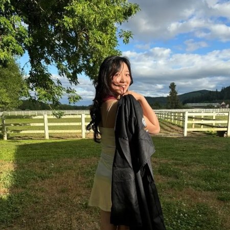 A woman in a dress holds a graduation gown.
