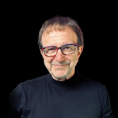 Vincent Racaniello wears a black shirt on a black background and has a playful smile.