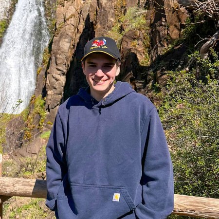 A man stands in front of a waterfall.