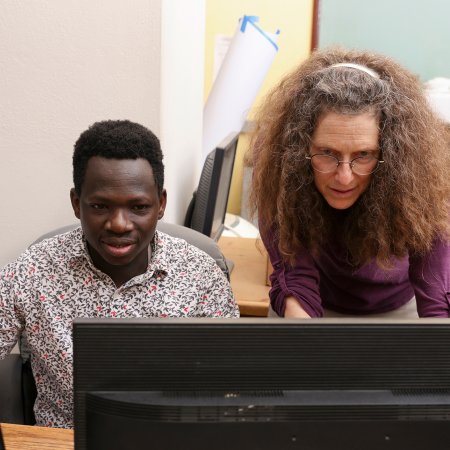 A professor and graduate student focus intensely on a computer screen as they work together.