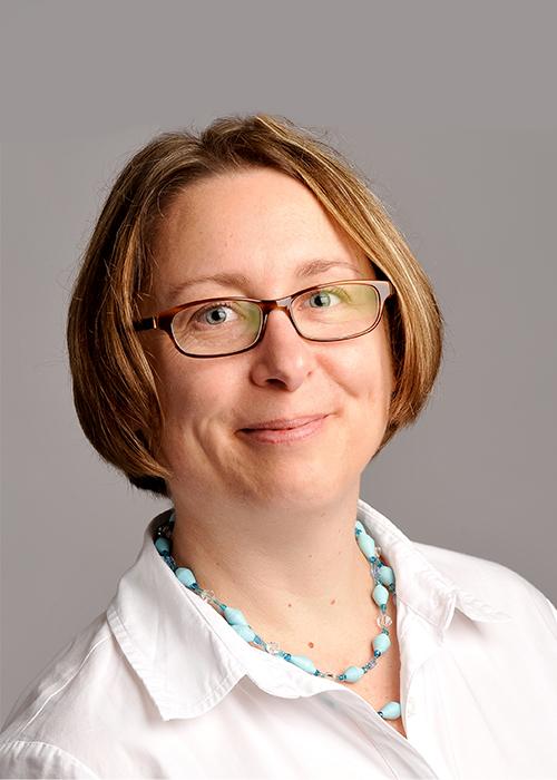 Marlys Amundson standing in front of a grey backdrop.