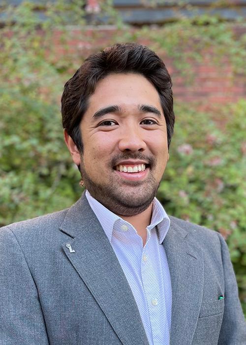 Kameron Kadooka standing in front of shrubbery.