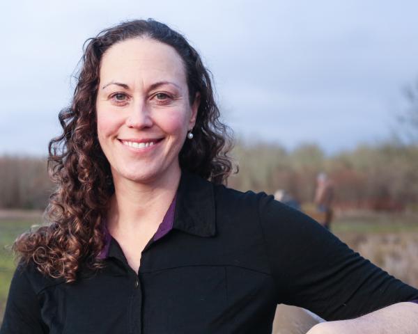 Headshot of Julie Alexander smiling on a riverbank