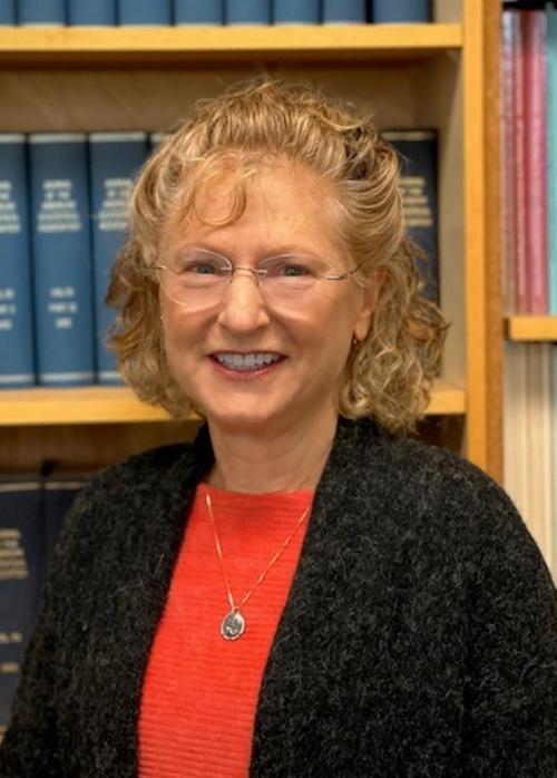 Headshot of Lisa Ganio smiling in front of a bookshelf full of books