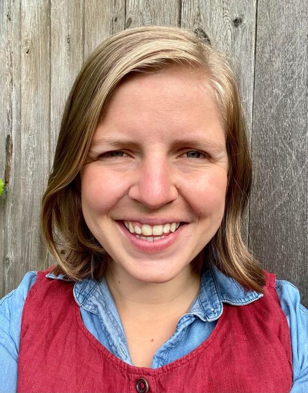 Picture of a woman with short blond hair and a red dress smiling.