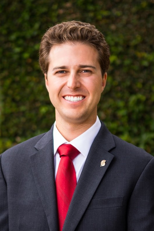 Smiling headshot of Chris in a suit and tie