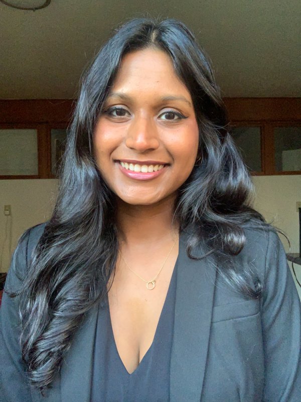 A smiling headshot of Sanjana Curtis in a blazer
