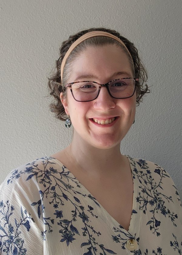 Portrait of Alice Naftaly standing against a white wall.