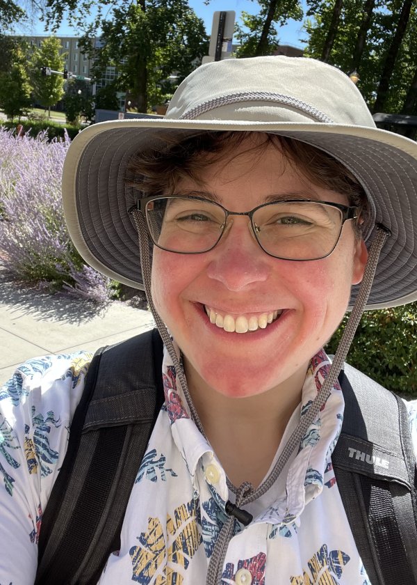 Ashely Stengel outside on a sunny day, wearing a hat and a backpack.