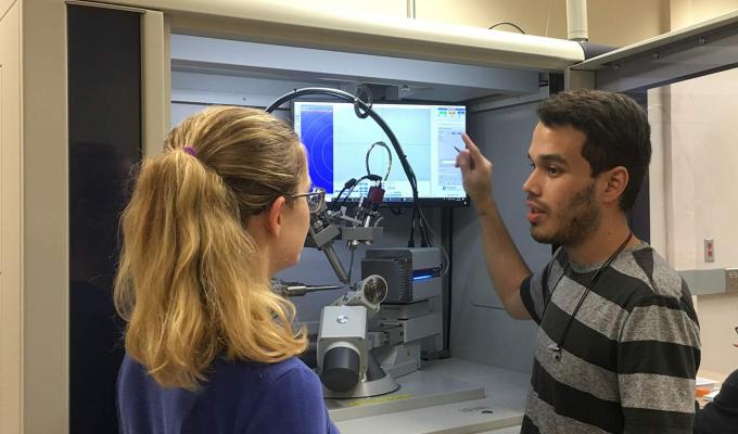 male and female students looking over lab machinery