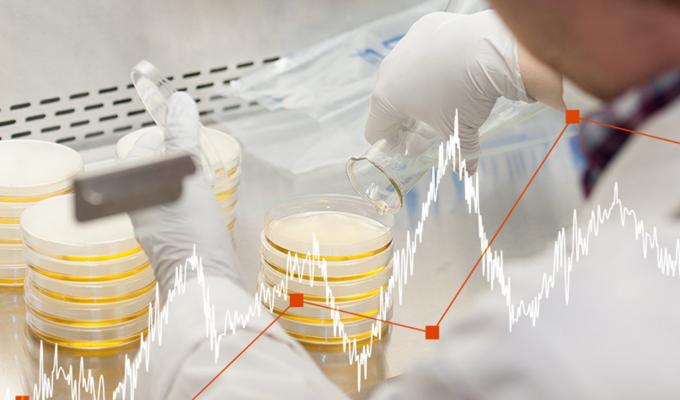 line graph icon above a scientist working with beakers in a lab
