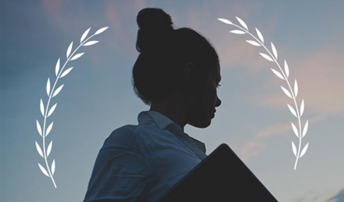 laurel icon above student with book during sunset