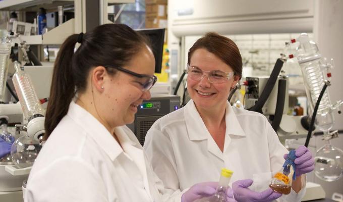 Sandra Loesgen with Cassandra Lew holding beakers in their lab