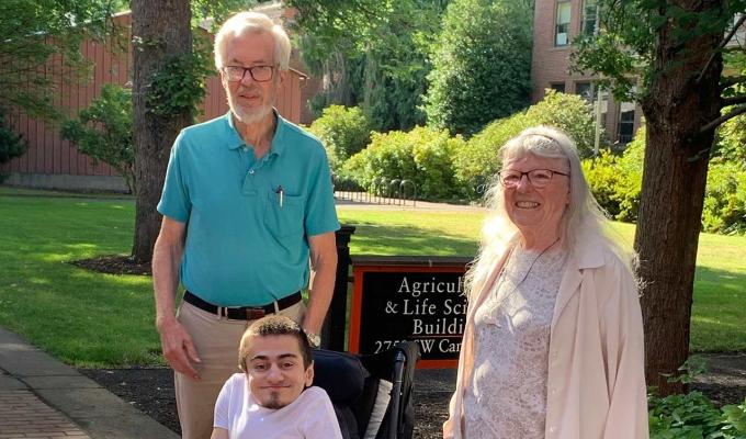 Patrick Morar taking photo with Chris and Catherine Mathews outside Agriculture & Life Sciences Building