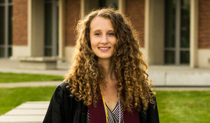 Sara Tro wearing graduation gown in front of the Learning Innovation Center