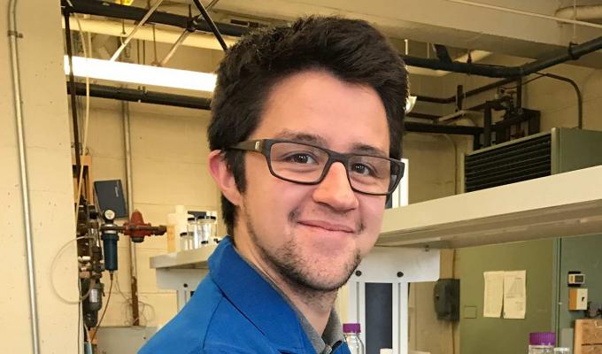 Collin Nicholas Muniz wearing a blue lab coat in chemistry lab