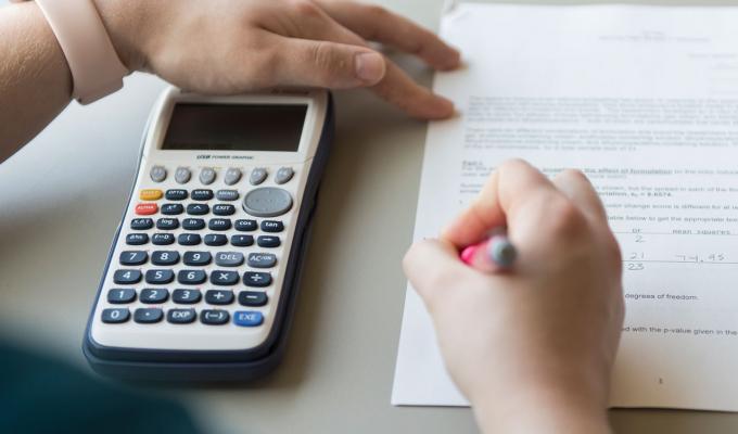 student working on math homework holding calculator