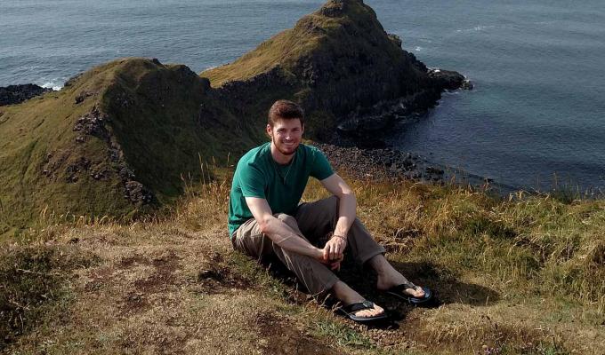 Nathan Jespersen sitting on an ocean viewpoint