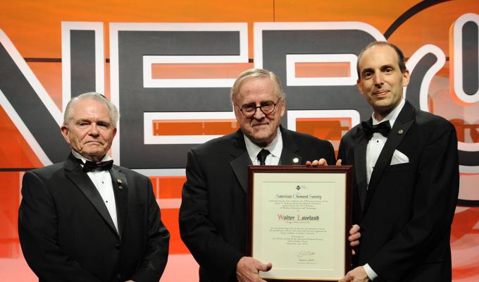 Walter Loveland receiving award on stage with two men on stage