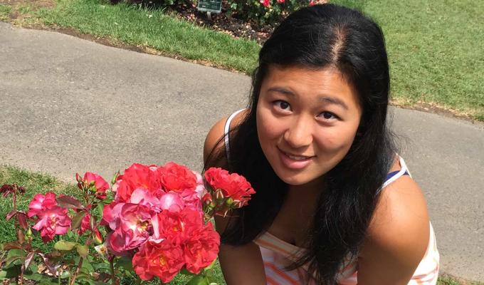 Stephanie Zhao standing next to roses in garden