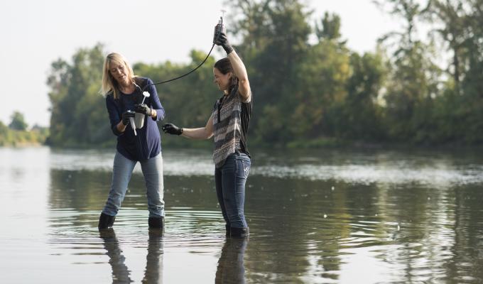 Kim Halsey with graduate student taking samples from a river