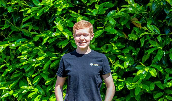 Mathew Frischman standing in front of a green bush