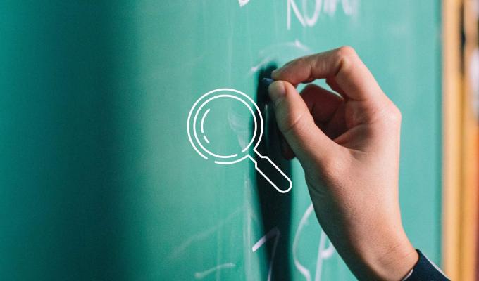 Magnifying glass icon above image of handing writing on chalkboard