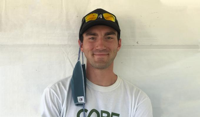 Zack Bango smiling in front of a white background, wearing a CORE shirt