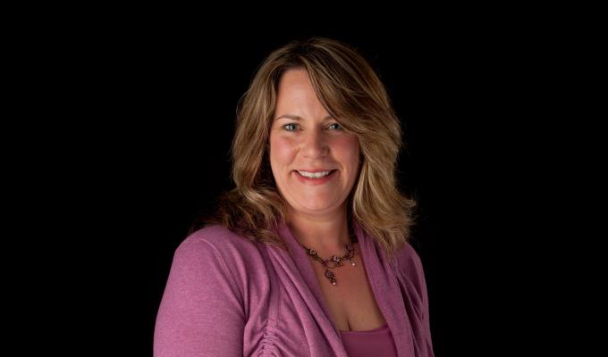Staci Simonich standing in front of black backdrop