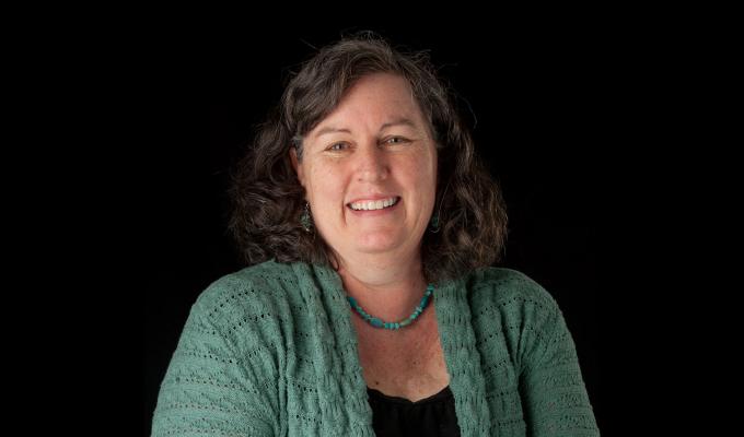 Margie Haak standing in front of black backdrop