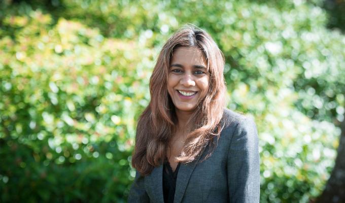 Vrushali Bokil standing in front of shrubbery.