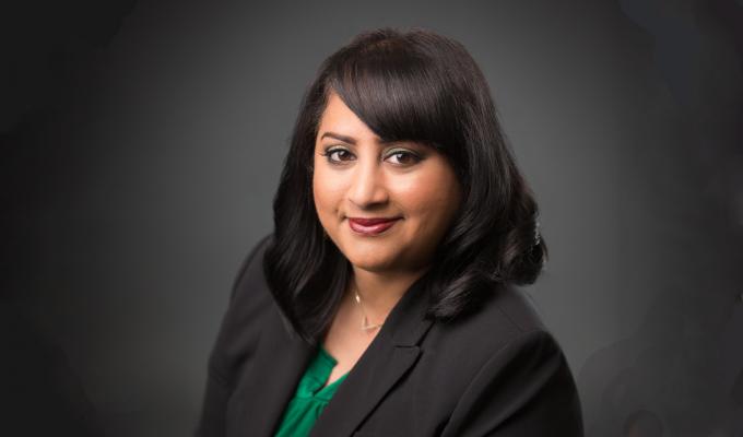 Marilyn Mackiewicz standing in front of a grey backdrop.