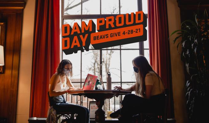 Dam Proud Day logo above an image of two students studying in the Memorial Union lounge.