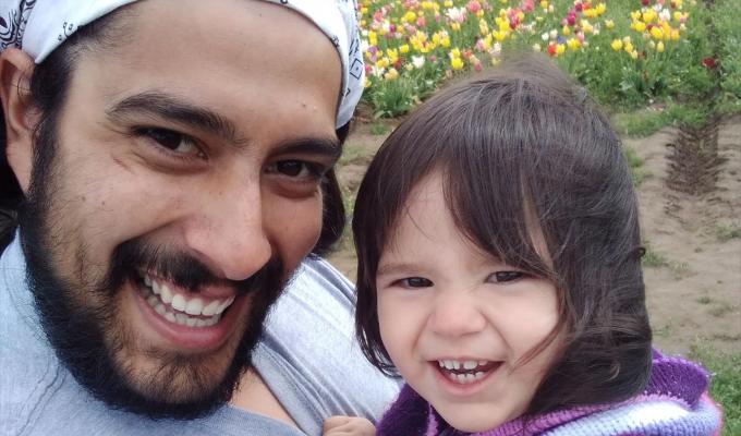 Oregon State physics graduate with daughter amid tulips.