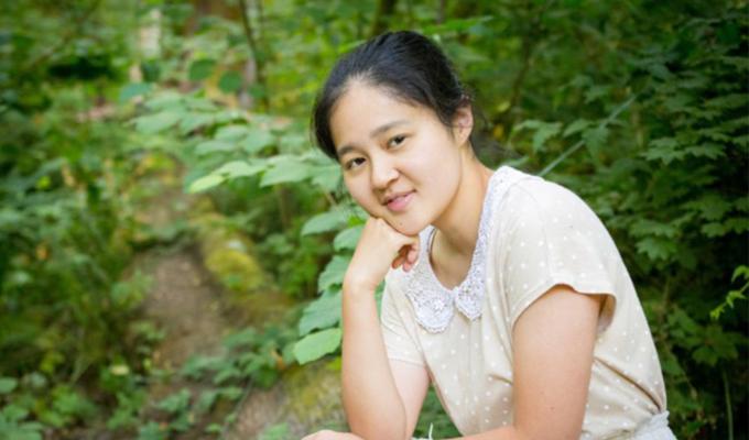 Saki Nakai sitting outside in a forest. 