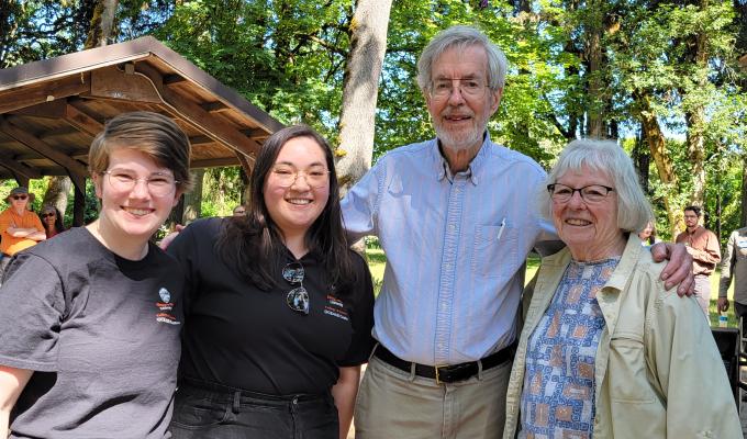 Moriah Mathis, Sarah Louie, Chris Mathews, and Kate Mathews stand outside smiling, with arms wrapped around each other.