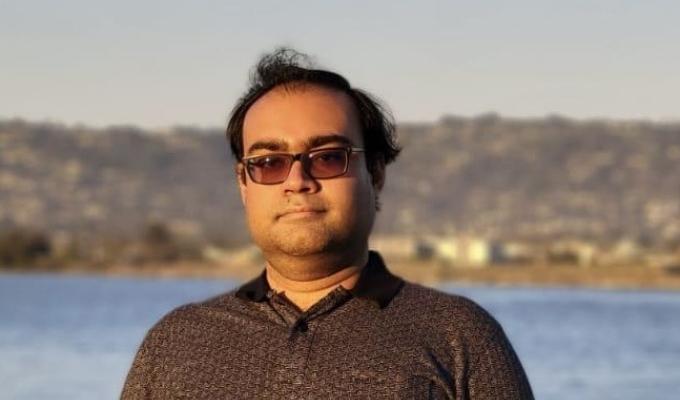 Sharmodeep Bhattacharyya stands in front of water in the background.