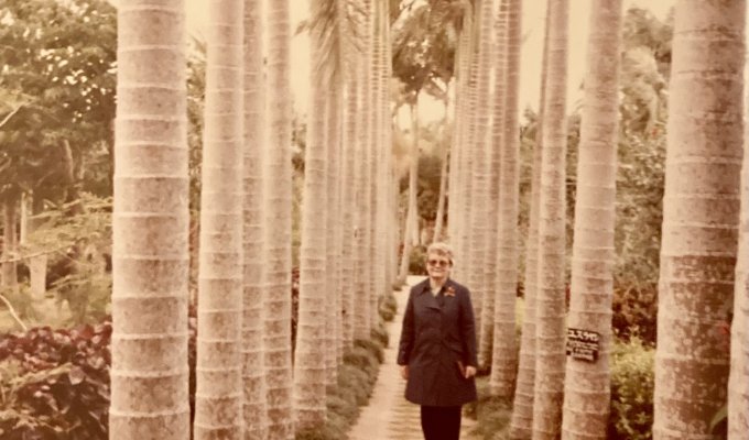 Eleanor Ford stands on a stone pathway with palm trees in Okinawa, Japan in 1981.