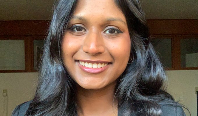 A smiling headshot of Sanjana Curtis in a blazer