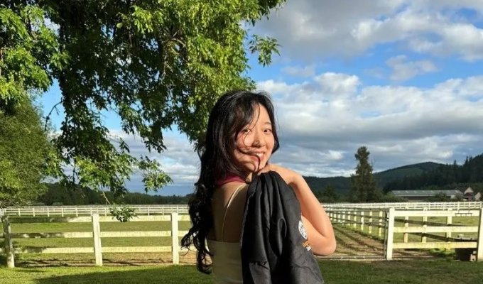 A woman in a dress holds a graduation gown.