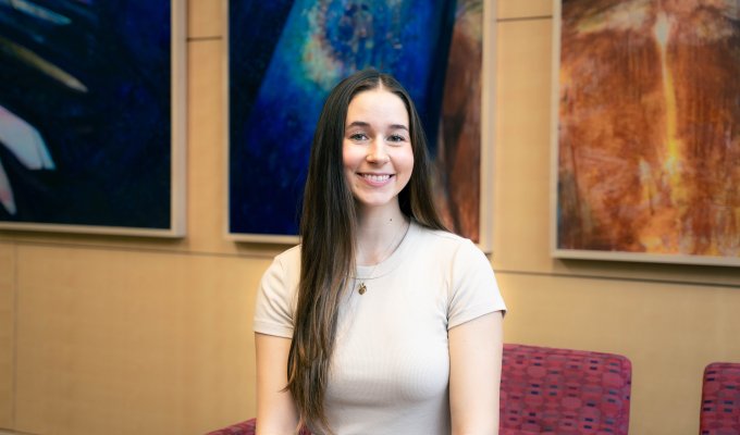 Kennedy Duff smiles for the camera in front of three colorful portraits.