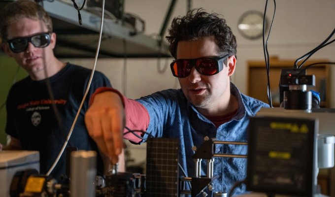 A man works in a laboratory with lazers and glasses.