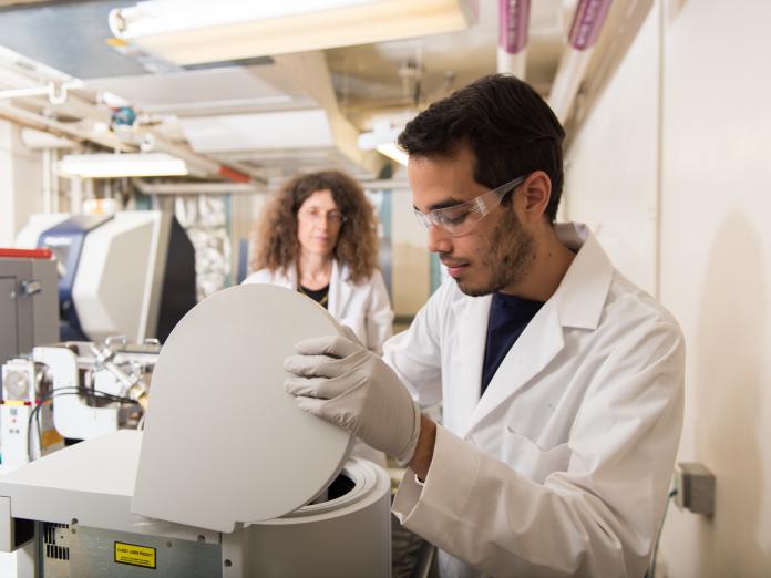 A student working in a chemistry lab under the supervision of May Nyman