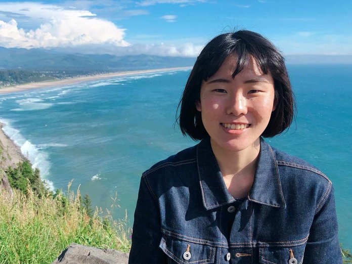 Mai Sakuragi in front of a coastal view