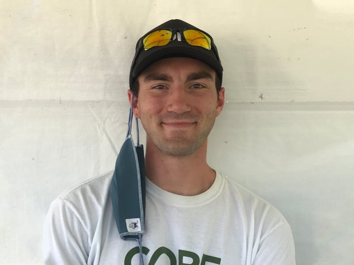 Zack Bango smiling in front of a white background, wearing a CORE shirt