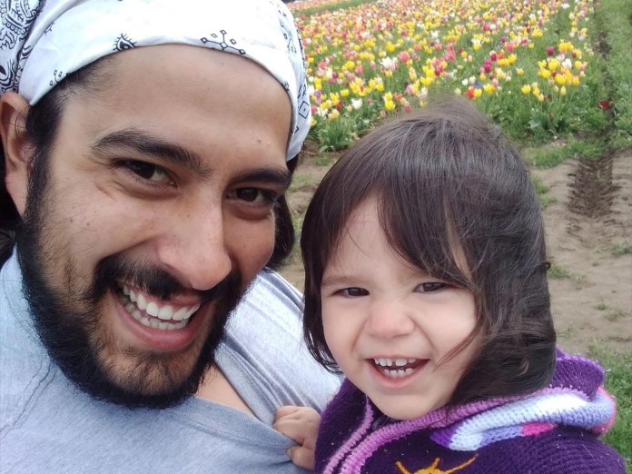 Oregon State physics graduate with daughter amid tulips.