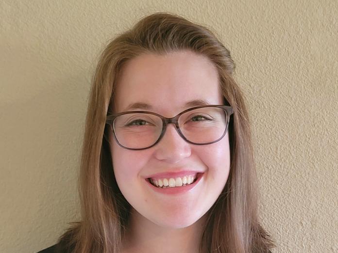 Taylor Bundy, a woman smiling and wearing glasses.