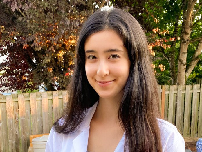 Gretchen Fujimura standing outside in a white lab coat. 
