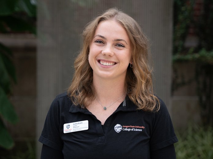 Audrey smiles while standing outside a building on campus