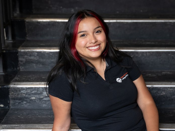 Jazmin smiles and poses on the stairs in Kidder Hall